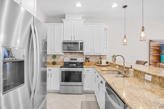 kitchen with stainless steel appliances, sink, hanging light fixtures, white cabinetry, and backsplash