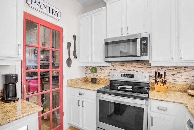 kitchen featuring appliances with stainless steel finishes, light stone counters, white cabinetry, and tasteful backsplash