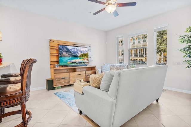 living area with baseboards, a ceiling fan, and light tile patterned flooring