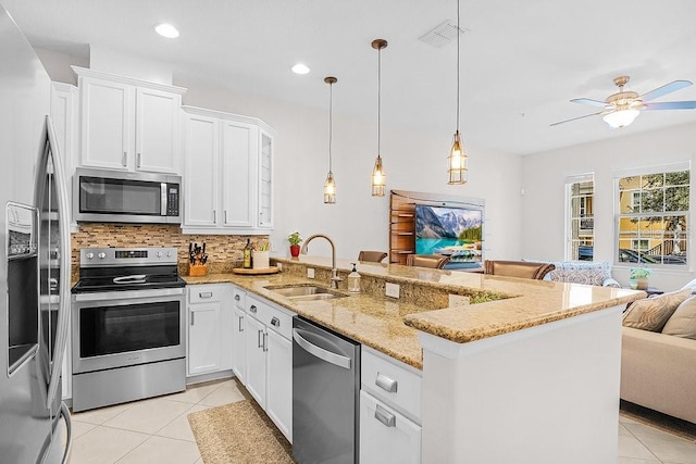 kitchen featuring light tile patterned floors, stainless steel appliances, open floor plan, a sink, and a peninsula