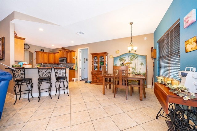 kitchen with a breakfast bar, kitchen peninsula, a notable chandelier, light tile patterned floors, and backsplash