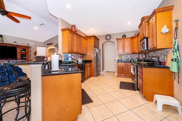 kitchen with stainless steel appliances, kitchen peninsula, backsplash, a kitchen bar, and lofted ceiling