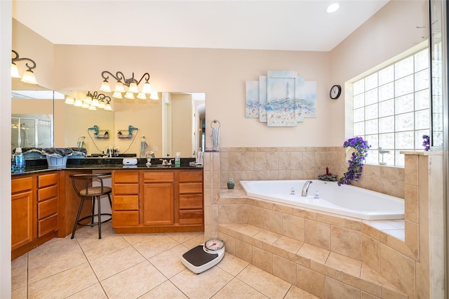 bathroom featuring tile patterned flooring, vanity, and tiled bath