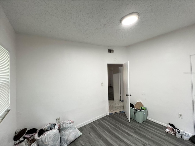 spare room featuring dark hardwood / wood-style floors and a textured ceiling