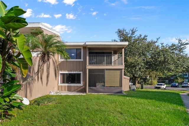 back of house with cooling unit, a balcony, and a lawn