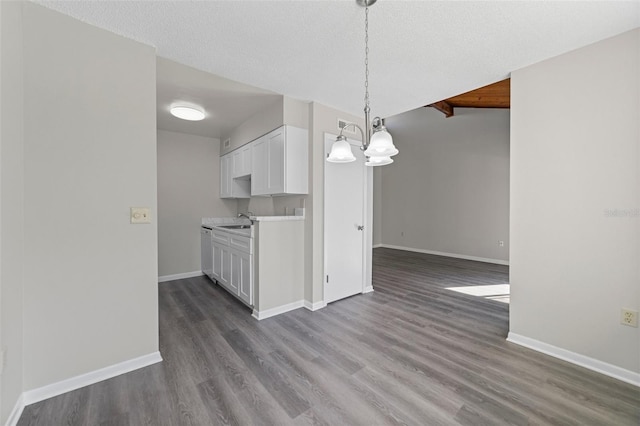 kitchen with wood-type flooring, dishwasher, hanging light fixtures, white cabinets, and a textured ceiling