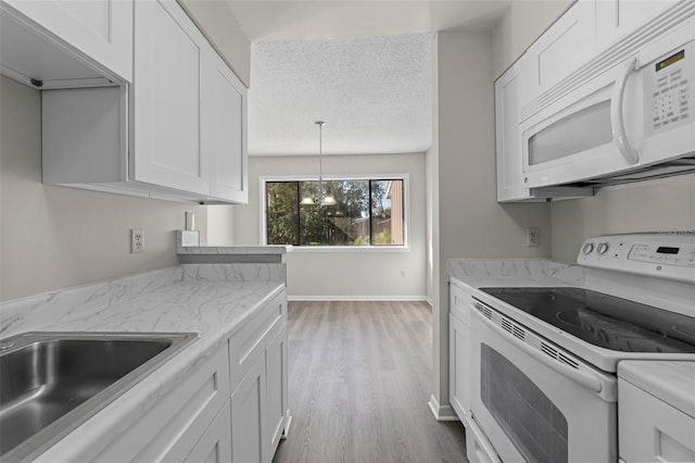 kitchen with light wood-type flooring, white appliances, white cabinetry, and a textured ceiling