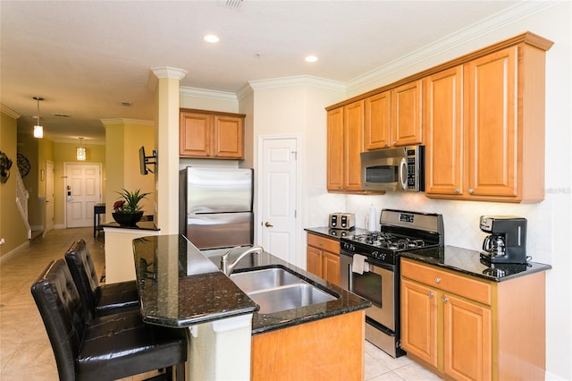 kitchen featuring sink, an island with sink, a kitchen breakfast bar, stainless steel appliances, and dark stone countertops