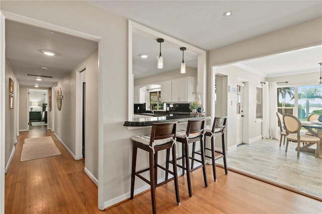 kitchen featuring white cabinets, light hardwood / wood-style flooring, tasteful backsplash, and kitchen peninsula