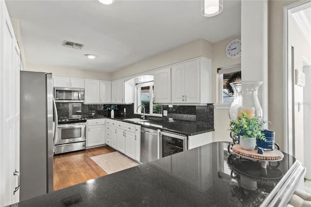 kitchen with wine cooler, white cabinets, stainless steel appliances, and sink