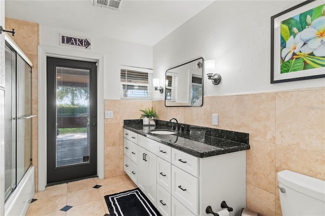 full bathroom featuring tile walls, vanity, toilet, and tile patterned flooring