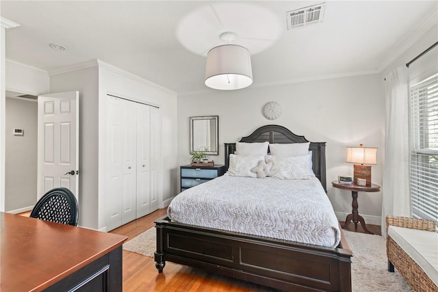 bedroom featuring ornamental molding, light wood-type flooring, and a closet