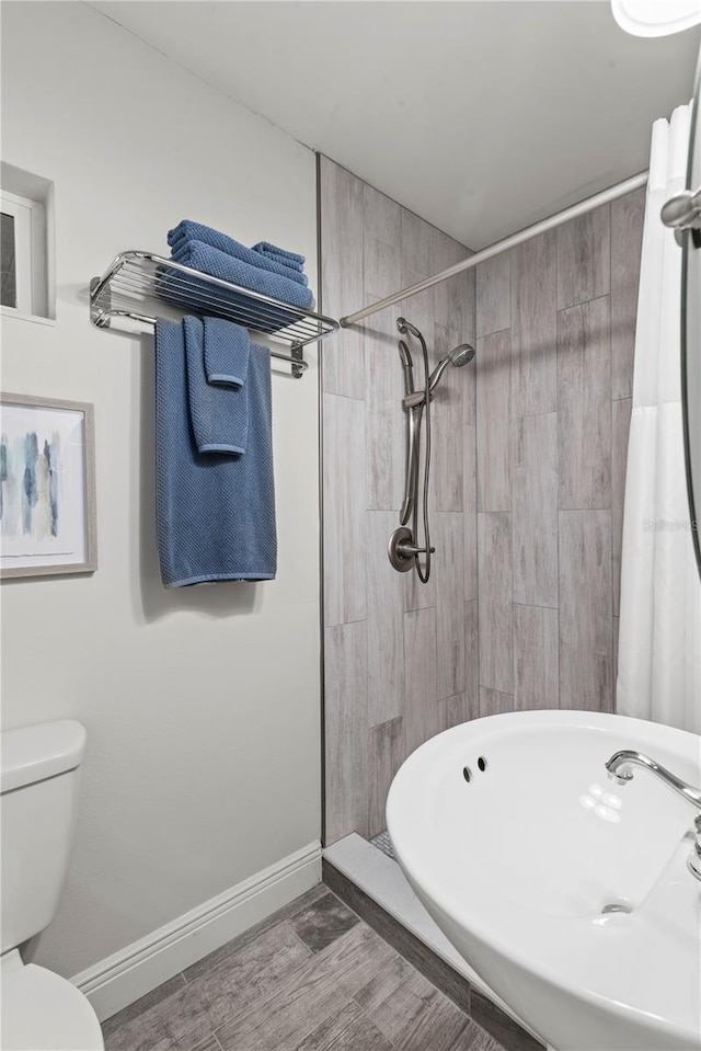 bathroom featuring toilet, wood-type flooring, and a shower with curtain