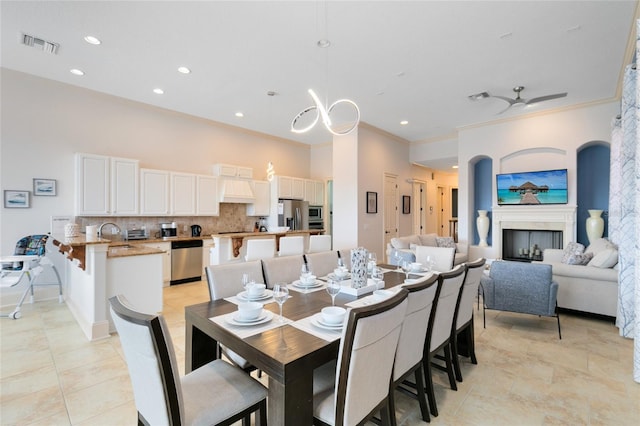 dining space featuring sink, ceiling fan, ornamental molding, and light tile patterned floors