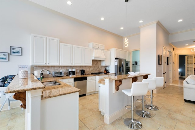 kitchen with appliances with stainless steel finishes, sink, kitchen peninsula, white cabinetry, and a breakfast bar