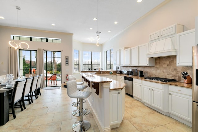 kitchen with hanging light fixtures, stainless steel appliances, sink, light stone countertops, and a center island