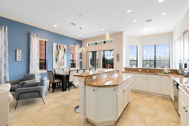 kitchen with sink, a kitchen island, white cabinetry, and a healthy amount of sunlight