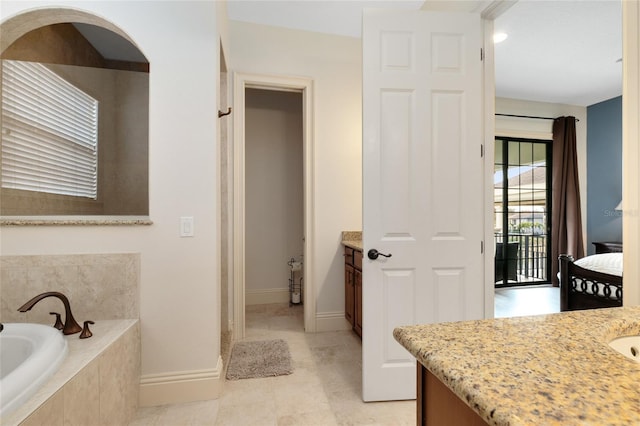 bathroom with vanity, tile patterned flooring, and tiled tub