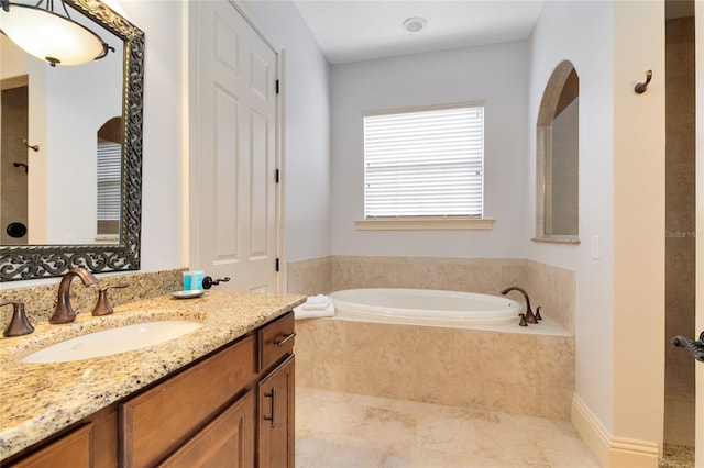 bathroom with vanity, tiled tub, and tile patterned flooring