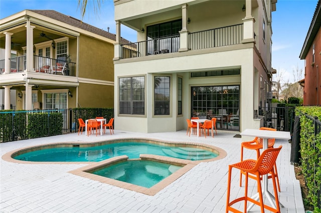 back of house featuring a patio, a pool with hot tub, and a balcony