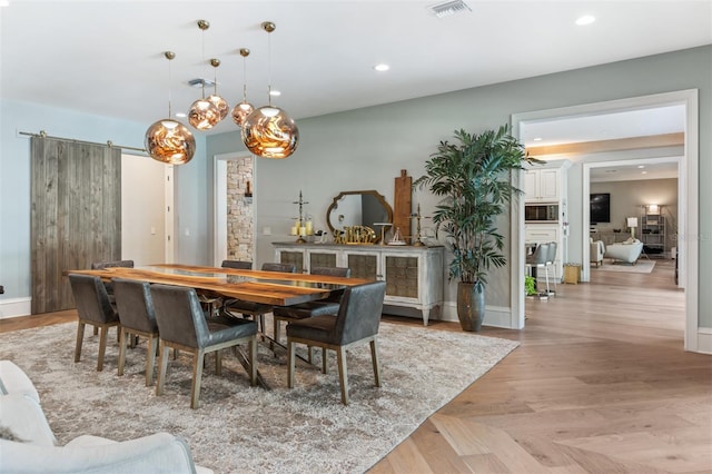 dining area with a barn door and light wood-type flooring