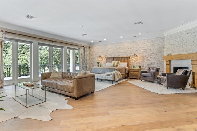 bedroom featuring a stone fireplace, crown molding, access to exterior, and light wood-type flooring