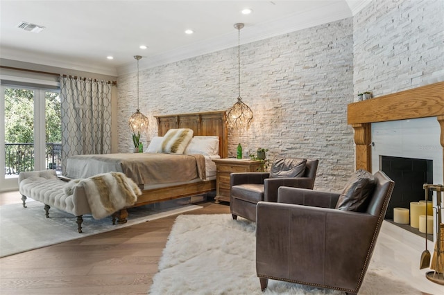 bedroom with light hardwood / wood-style flooring, crown molding, access to outside, and a fireplace