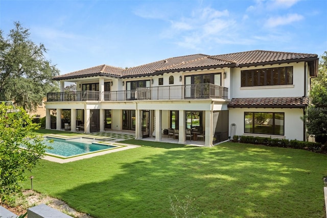 rear view of property with a balcony, a patio, and a lawn