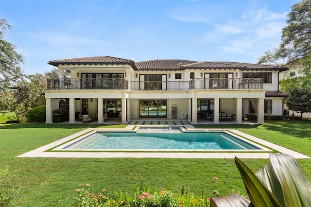 back of house featuring a yard, a patio, a balcony, and a swimming pool with hot tub