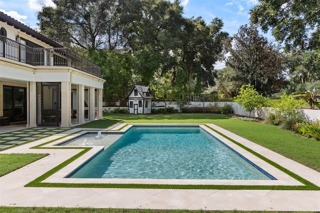 view of swimming pool featuring a storage unit, a yard, and a patio area