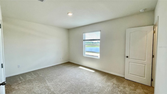 spare room featuring light carpet and a water view