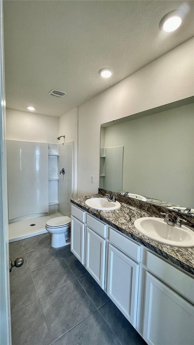 bathroom with a textured ceiling, walk in shower, vanity, and toilet