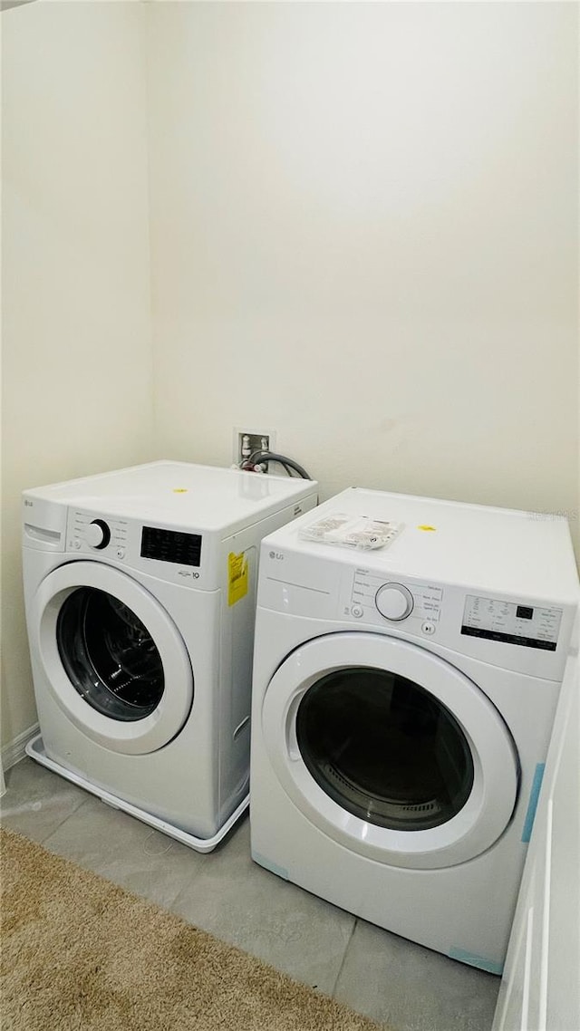 laundry area with washer and clothes dryer and light tile patterned floors