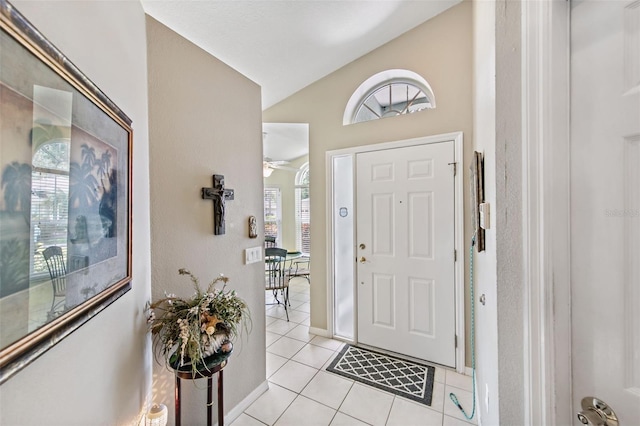 foyer entrance with light tile patterned floors, vaulted ceiling, and plenty of natural light