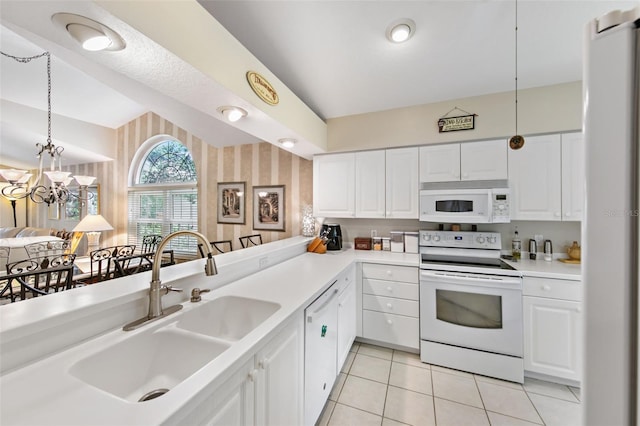 kitchen with white appliances, sink, kitchen peninsula, vaulted ceiling, and white cabinets