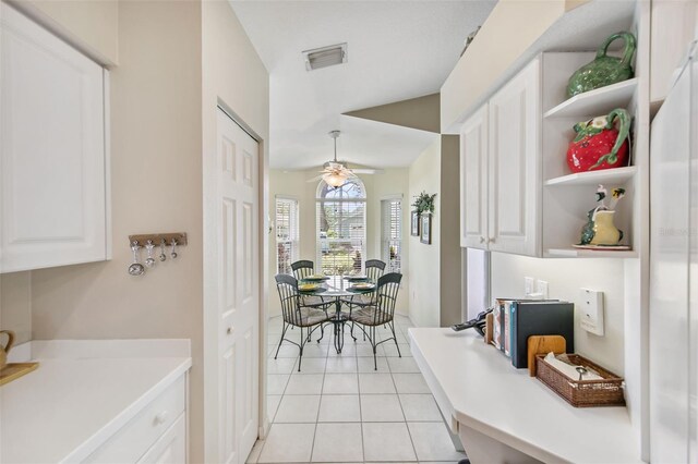 interior space with white cabinets, light tile patterned floors, and ceiling fan