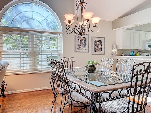 dining area featuring lofted ceiling, light hardwood / wood-style flooring, and a chandelier