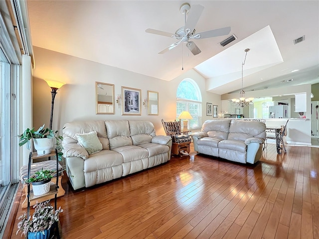 living room with hardwood / wood-style flooring, ceiling fan with notable chandelier, and vaulted ceiling