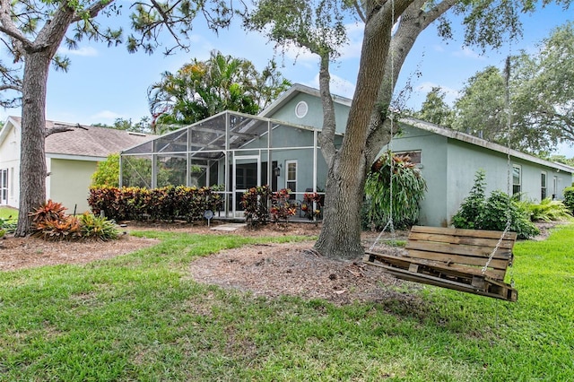 rear view of house with a yard and glass enclosure