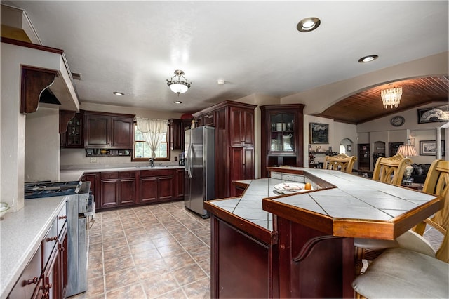 kitchen featuring appliances with stainless steel finishes, lofted ceiling, sink, and tile counters