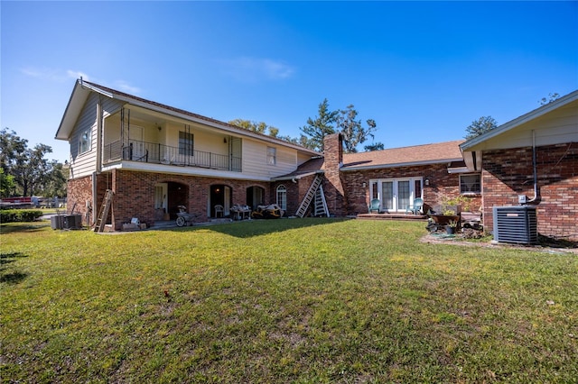 rear view of house with a lawn, a balcony, and cooling unit