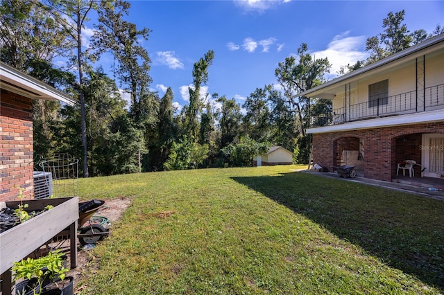 view of yard with central AC unit and a balcony