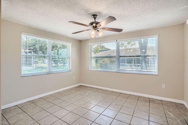 tiled empty room with a textured ceiling, plenty of natural light, and ceiling fan