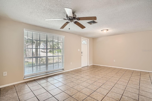 spare room featuring ceiling fan, a textured ceiling, and light tile patterned floors