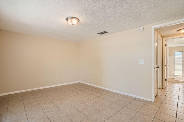 tiled spare room featuring a textured ceiling