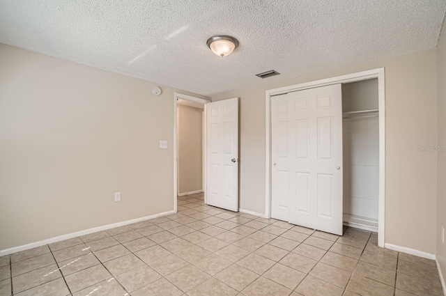 unfurnished bedroom with light tile patterned floors, a textured ceiling, and a closet