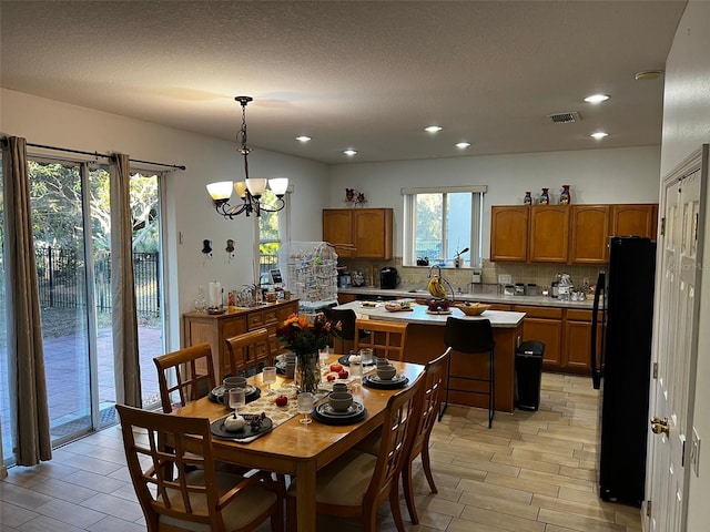 dining area featuring a textured ceiling, light wood-type flooring, and a notable chandelier