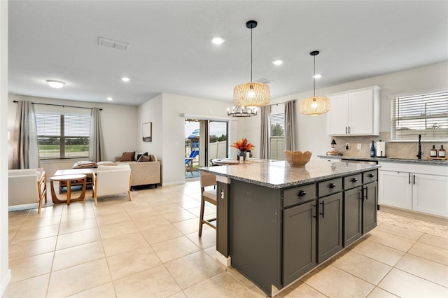 kitchen with white cabinets, a center island, sink, and pendant lighting