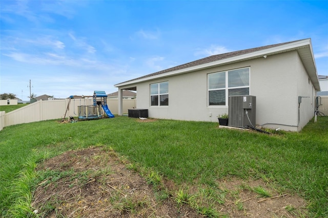 back of house with central AC and a yard