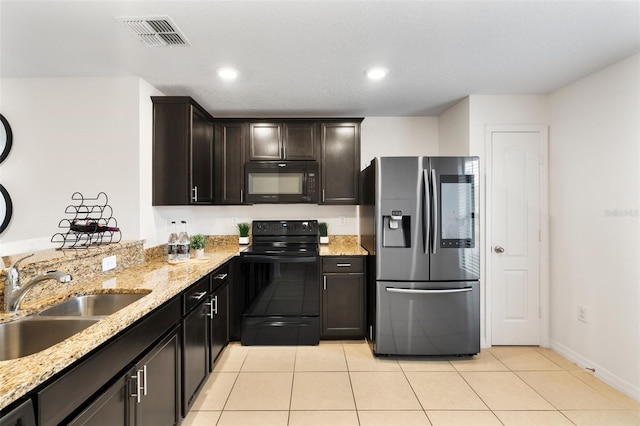 kitchen with sink, light tile patterned floors, light stone counters, black appliances, and dark brown cabinetry